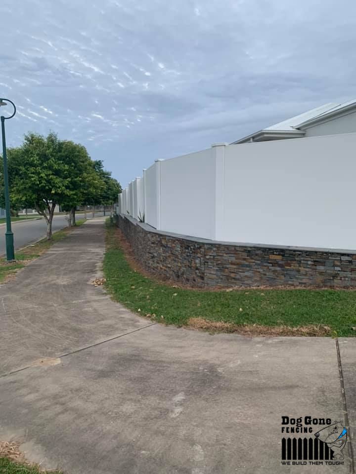 A White Fence Is Surrounded By Grass And Trees Next To A Sidewalk — Dog Gone Fencing in Paget, QLD