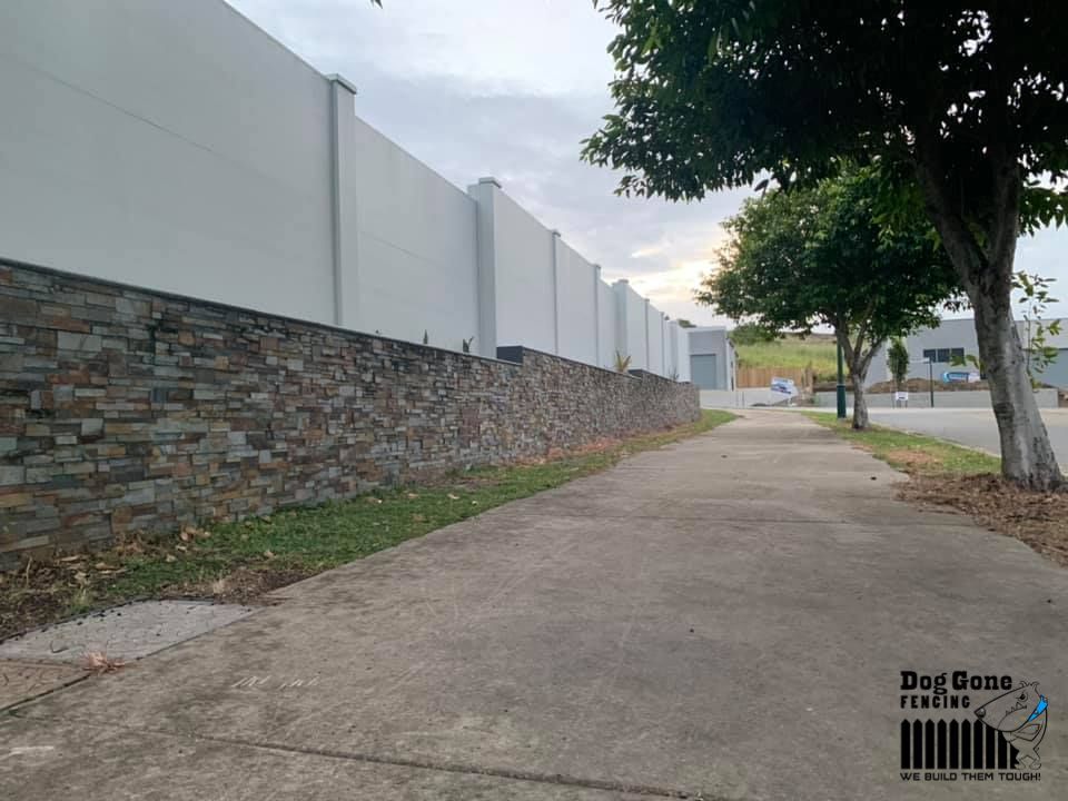 A Sidewalk With A Stone Wall On The Side Of It — Dog Gone Fencing in Paget, QLD