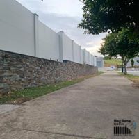 A Sidewalk With A Stone Wall On The Side Of It — Dog Gone Fencing in Paget, QLD