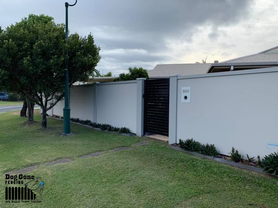 A White Fence With A Black Gate In Front Of A House — Dog Gone Fencing in Paget, QLD