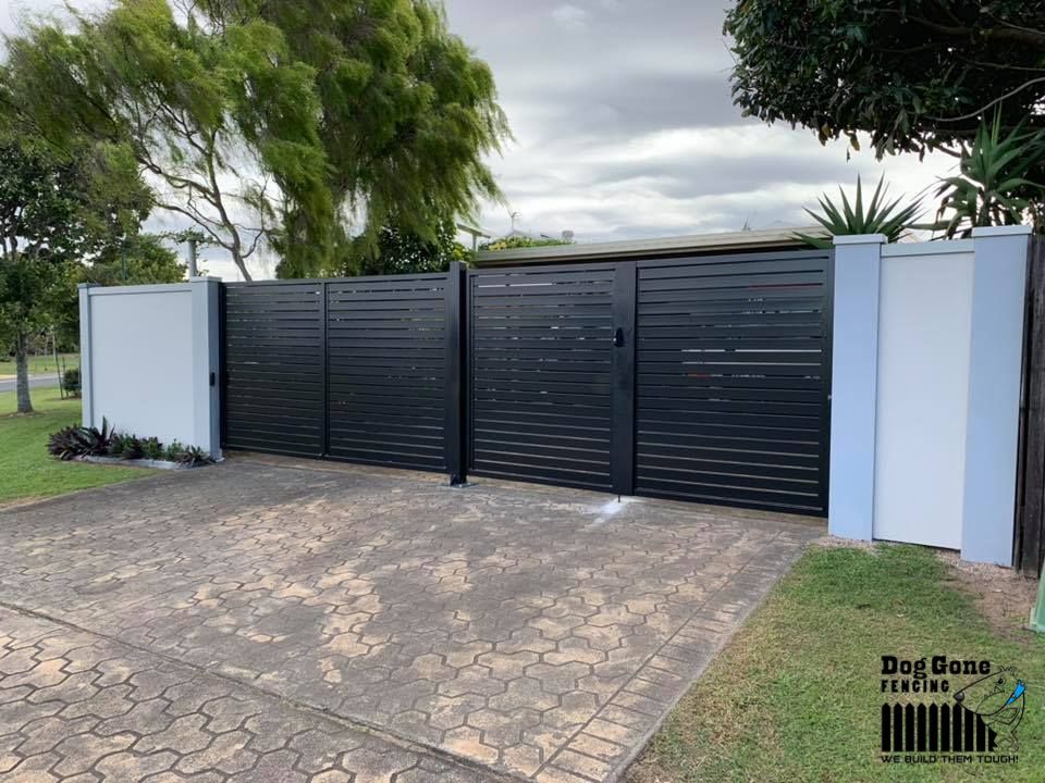 A Black Fence Is Surrounding A Driveway In Front Of A House — Dog Gone Fencing in Paget, QLD