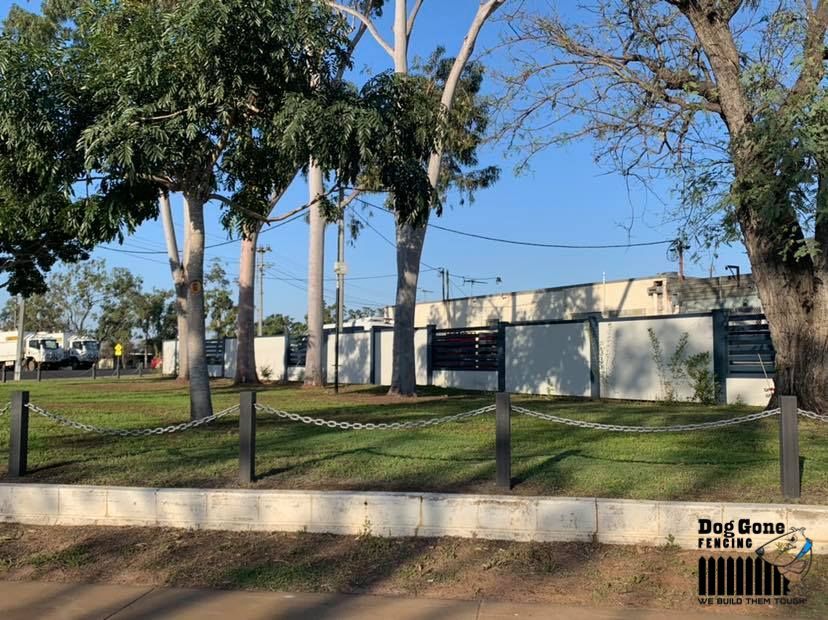 A Fenced In Area With Trees And A Building In The Background — Dog Gone Fencing in Paget, QLD