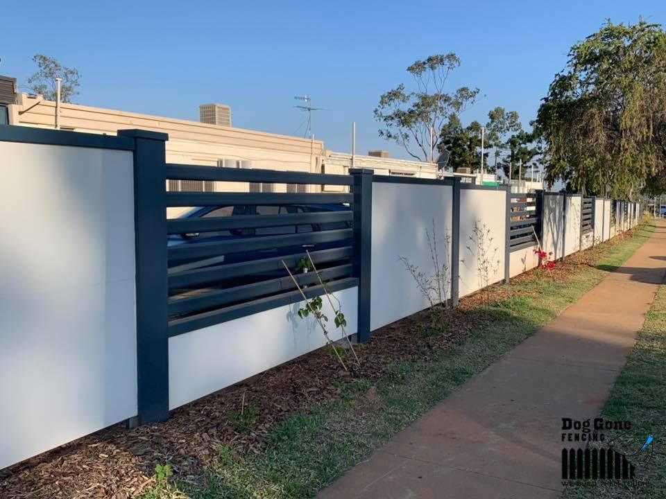 A Black And White Fence Along A Sidewalk Next To A Building — Dog Gone Fencing in Paget, QLD