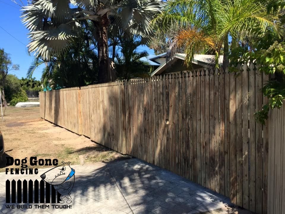 A Wooden Fence Surrounds A Driveway In Front Of A House — Dog Gone Fencing in Paget, QLD