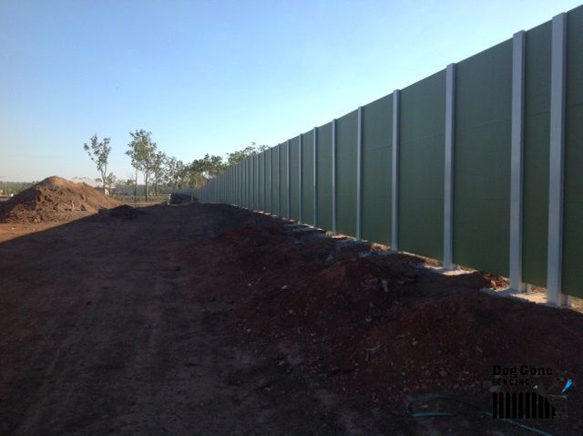 A Large Green Fence Surrounds A Dirt Field — Dog Gone Fencing in Paget, QLD
