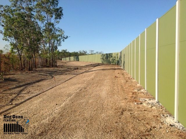 A Large Green Fence Surrounds A Dirt Road — Dog Gone Fencing in Paget, QLD