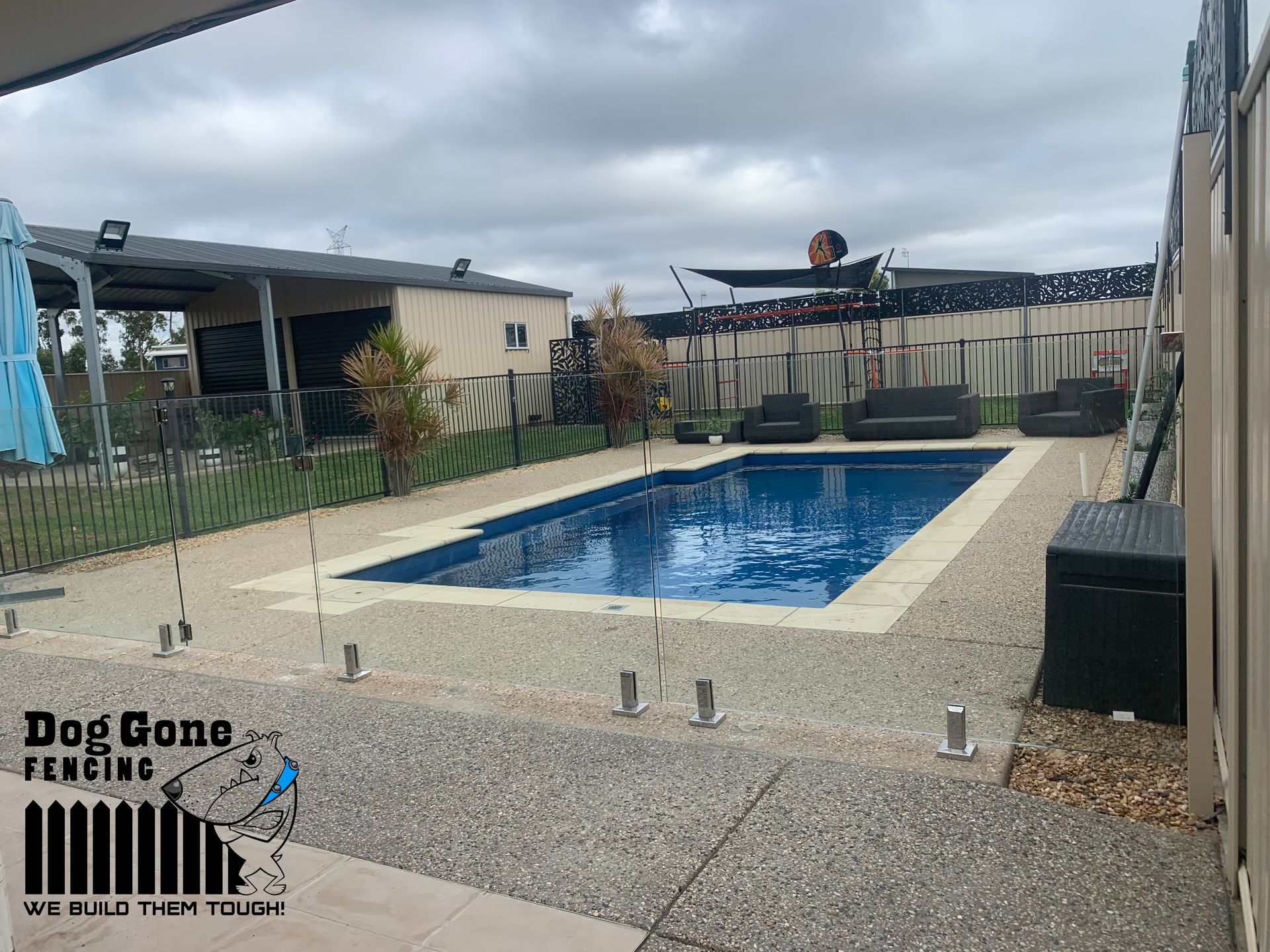A Large Swimming Pool Is Surrounded By A Fence And A House — Dog Gone Fencing in Paget, QLD