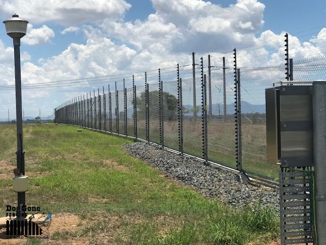 A Fence Is Surrounding A Grassy Field With A Street Light In The Foreground  — Dog Gone Fencing in Paget, QLD