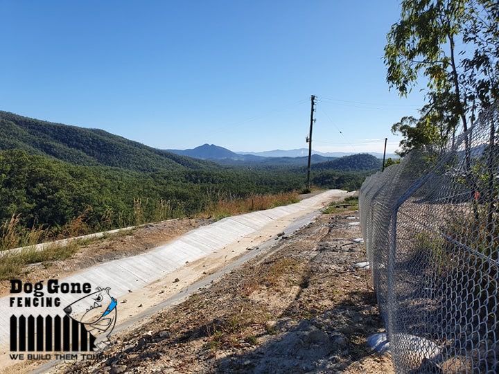 A Chain Link Fence Along A Dirt Road With Mountains In The Background  — Dog Gone Fencing in Paget, QLD