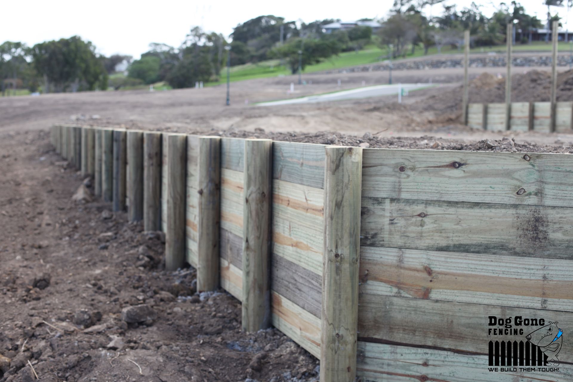 A Wooden Fence Is Being Built In A Dirt Field — Dog Gone Fencing in Paget, QLD