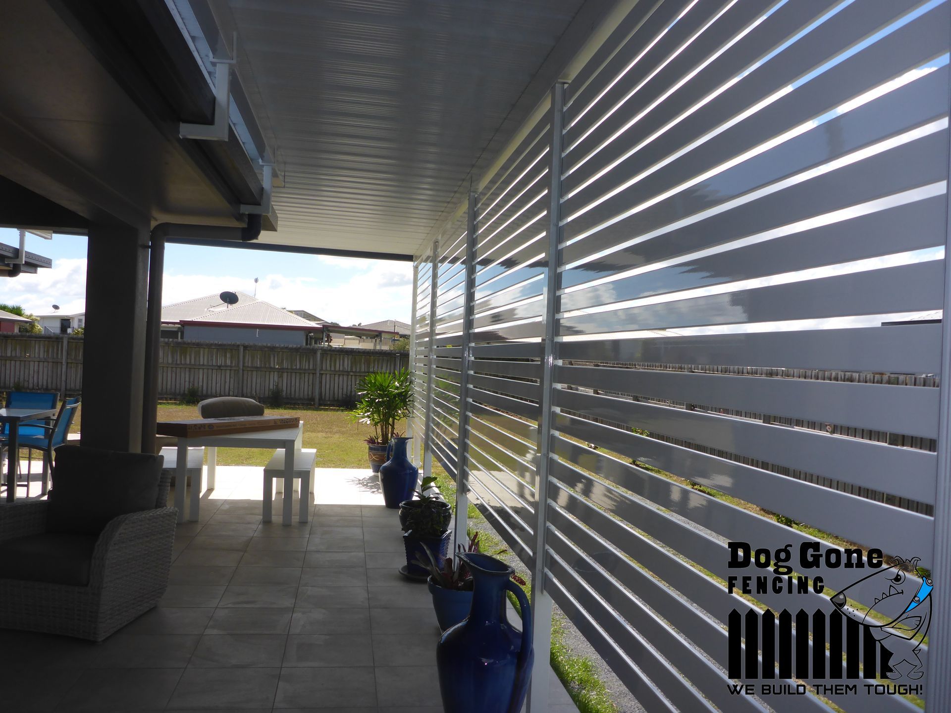 A White Fence Surrounds A Patio With A Table And Chairs — Dog Gone Fencing in Paget, QLD