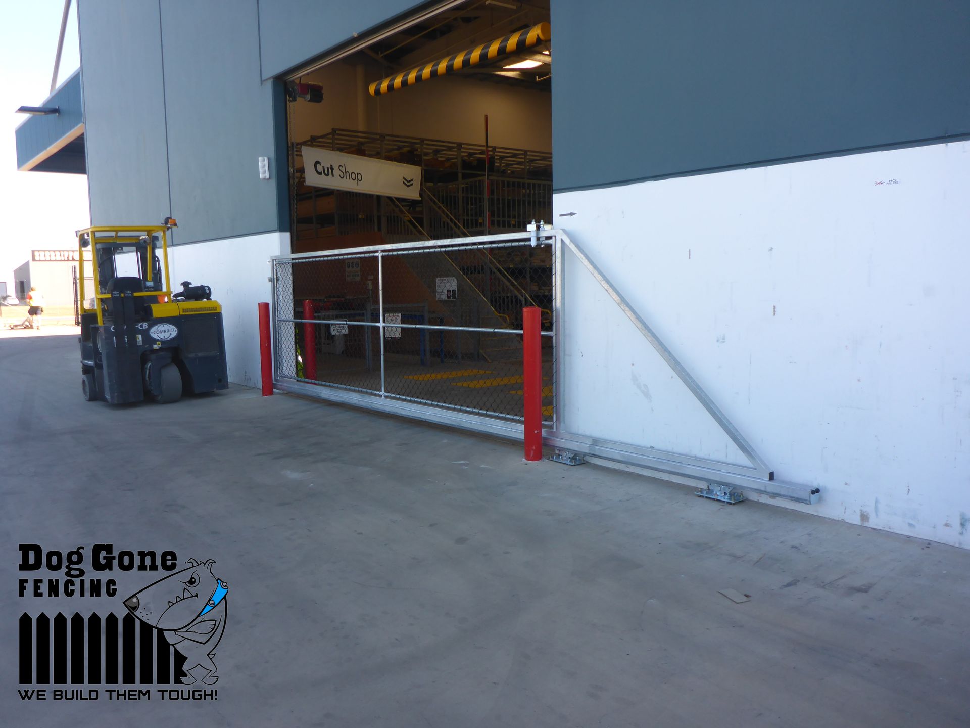 A Yellow Forklift Is Parked In Front Of A Building  — Dog Gone Fencing in Paget, QLD
