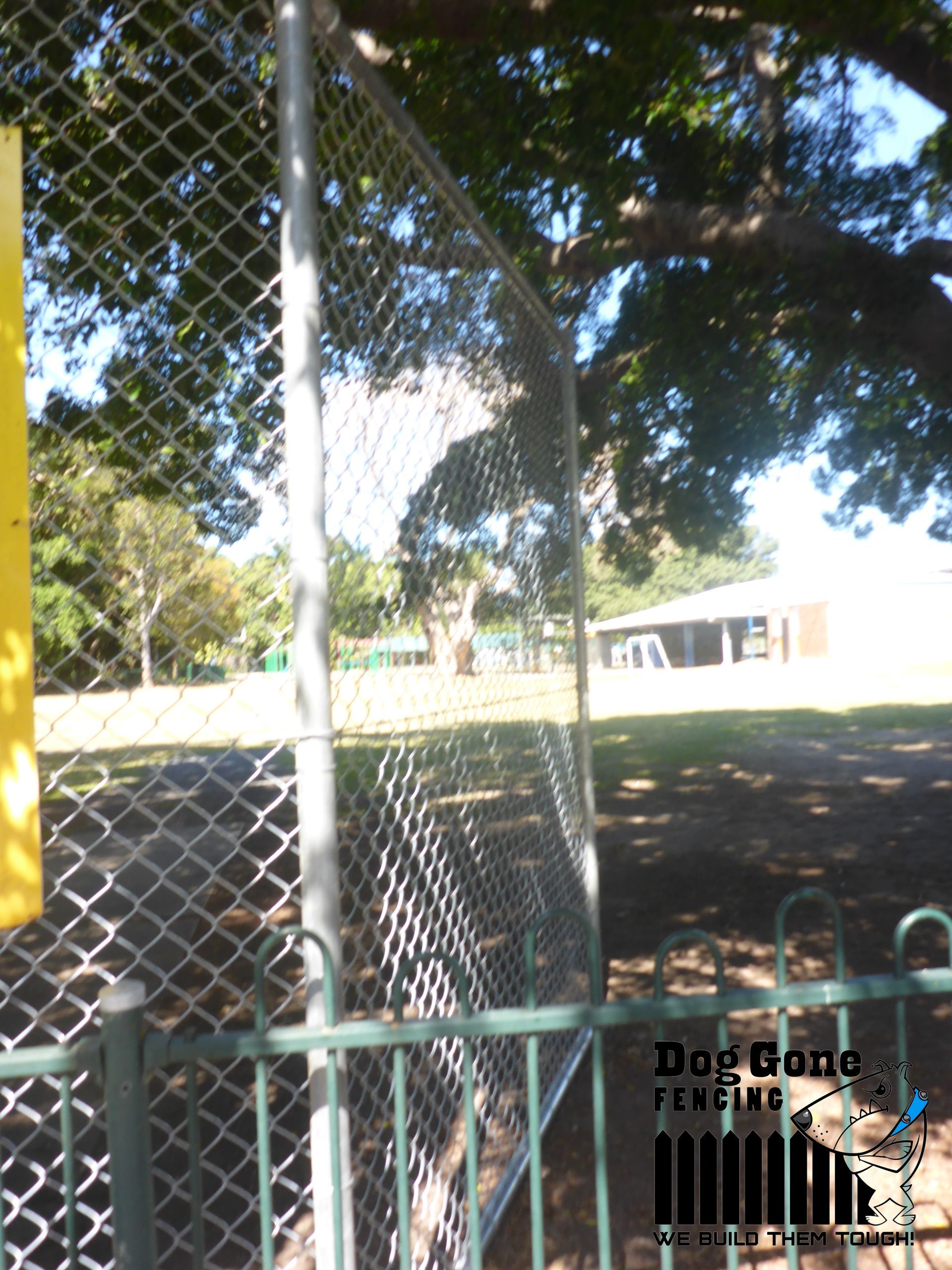 A Chain Link Fence With A Yellow Sign In The Background — Dog Gone Fencing in Paget, QLD