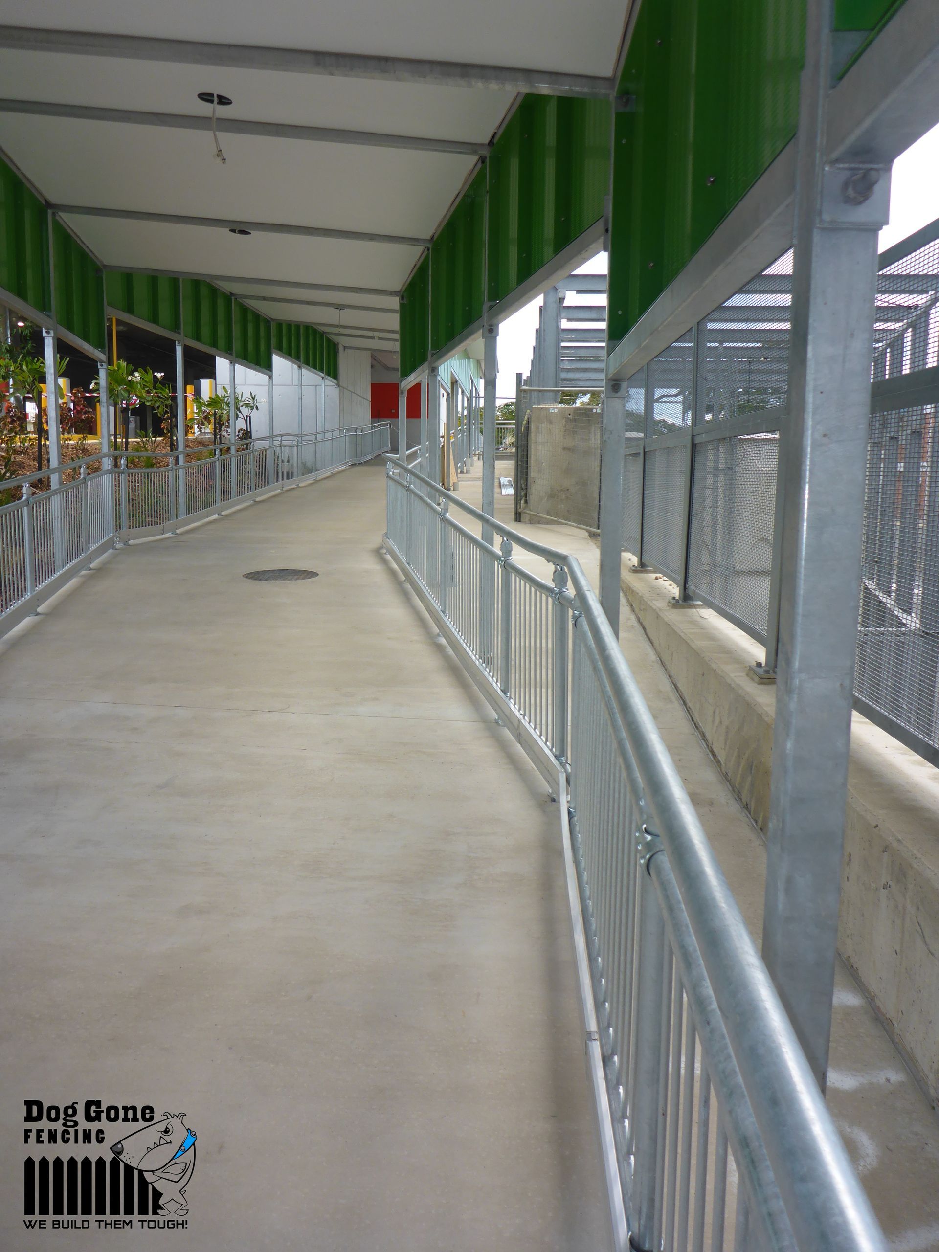 A Concrete Walkway With A Metal Railing And A Green Canopy — Dog Gone Fencing in Paget, QLD