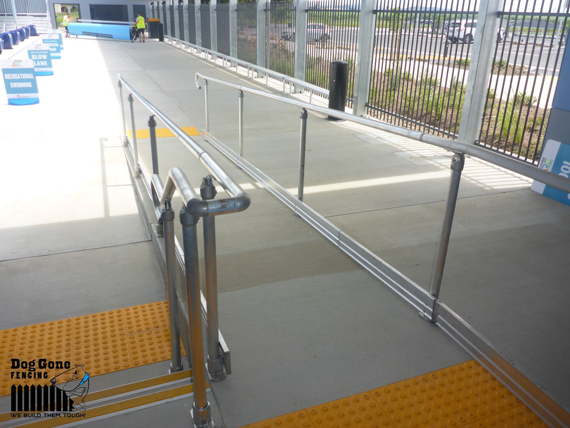 A Person Is Walking Across A Bridge With A Railing — Dog Gone Fencing in Paget, QLD