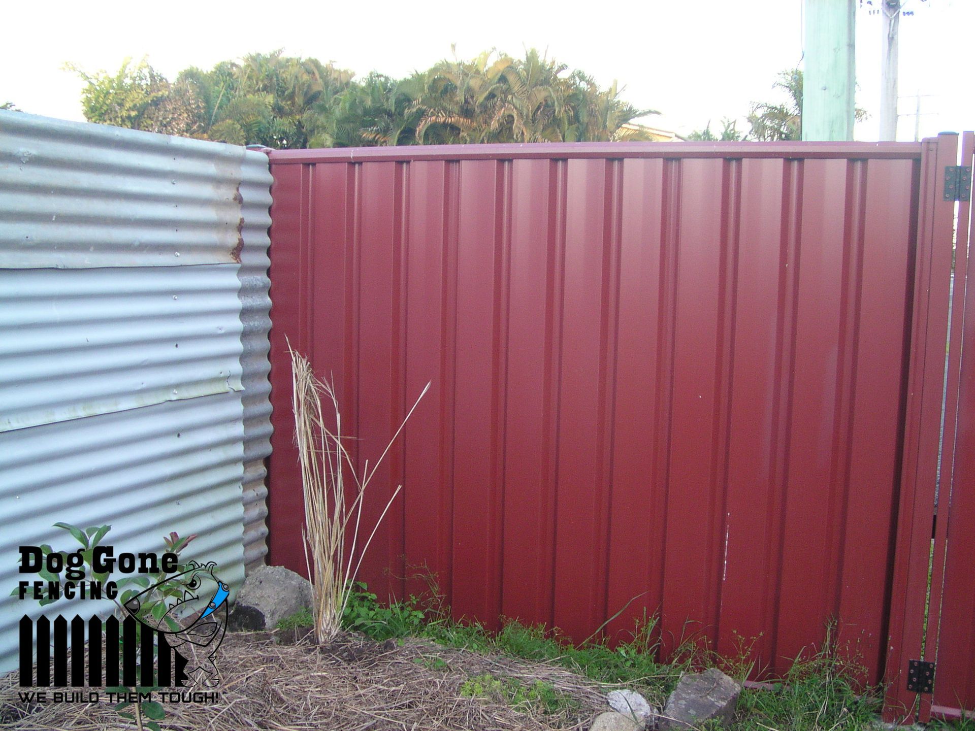A Red Fence Is Sitting Next To A White Fence — Dog Gone Fencing in Paget, QLD