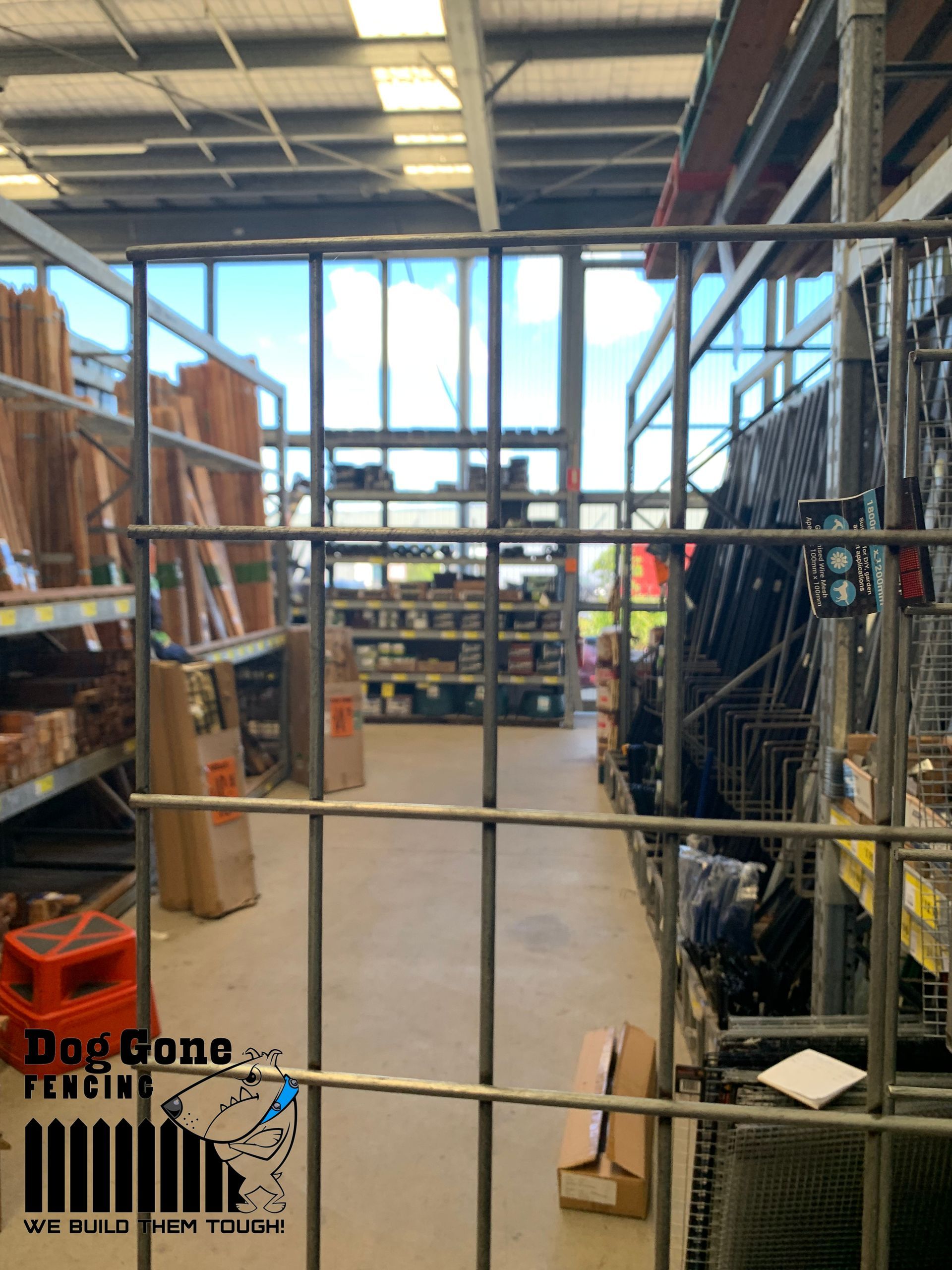 A Warehouse Filled With Lots Of Shelves And Boxes Behind A Fence — Dog Gone Fencing in Paget, QLD