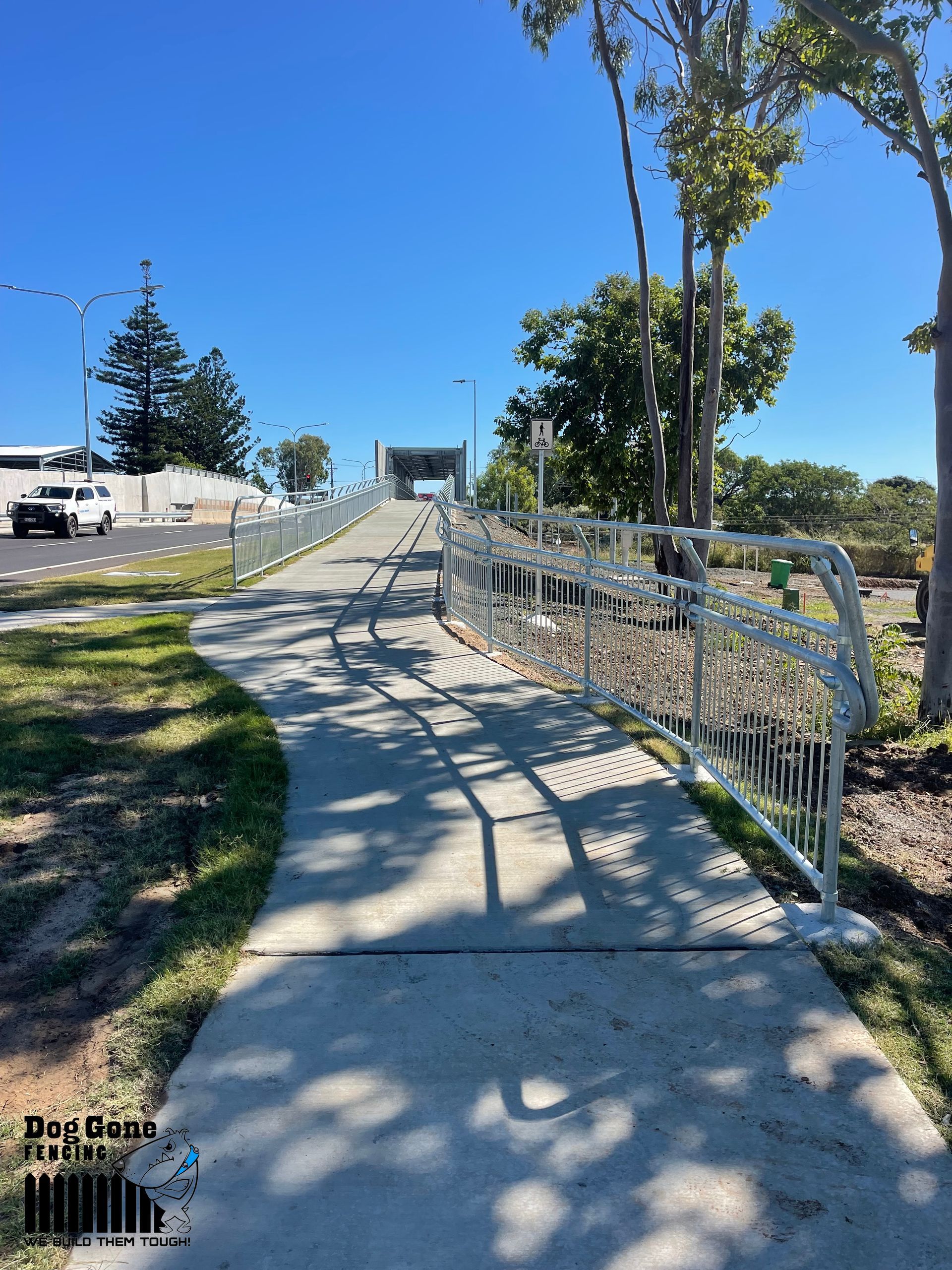 A Concrete Walkway With A Metal Railing Leading To A Bridge - Fencing in Mackay, QLD