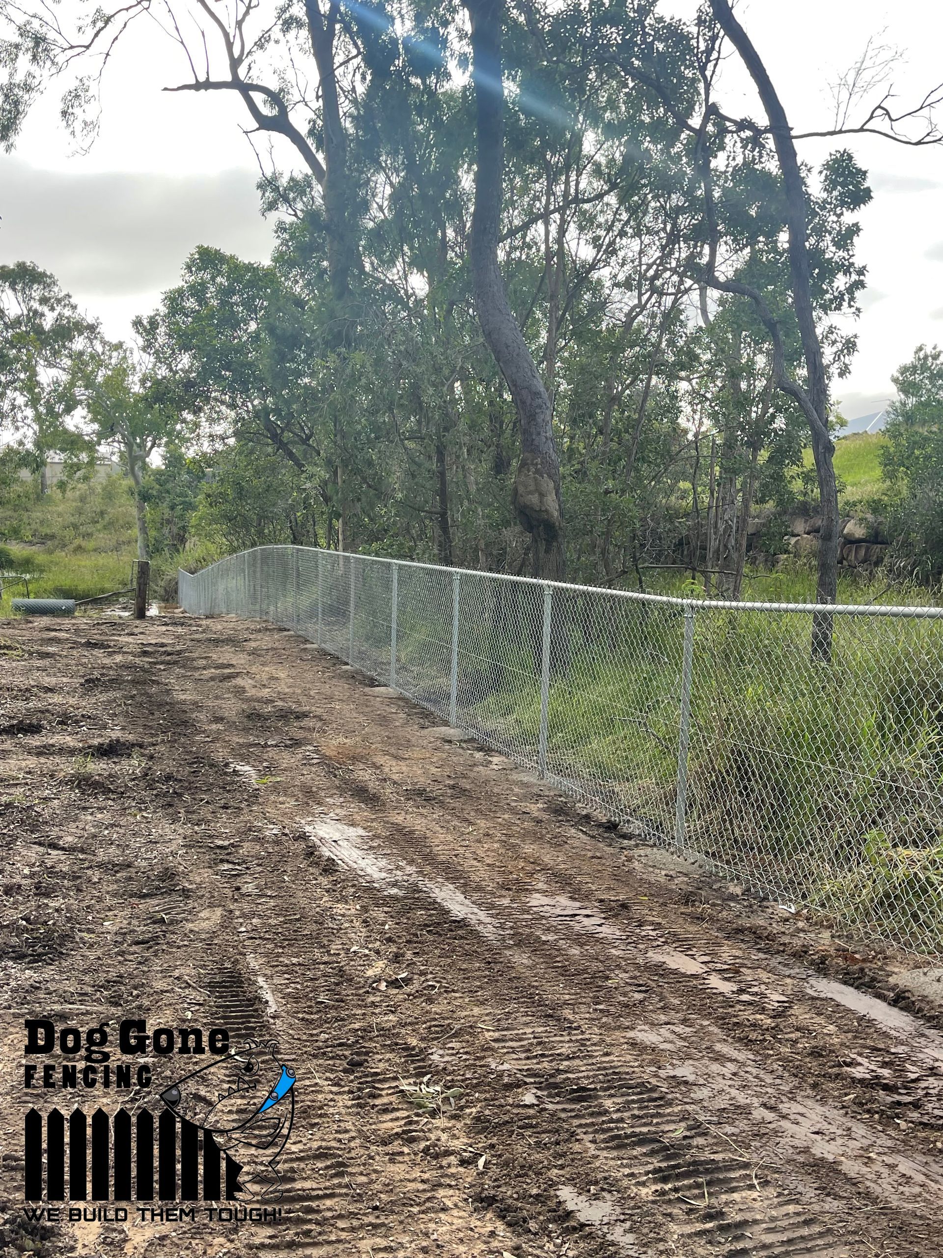 A Dirt Road Next To A Fence And Trees — Dog Gone Fencing in Paget, QLD