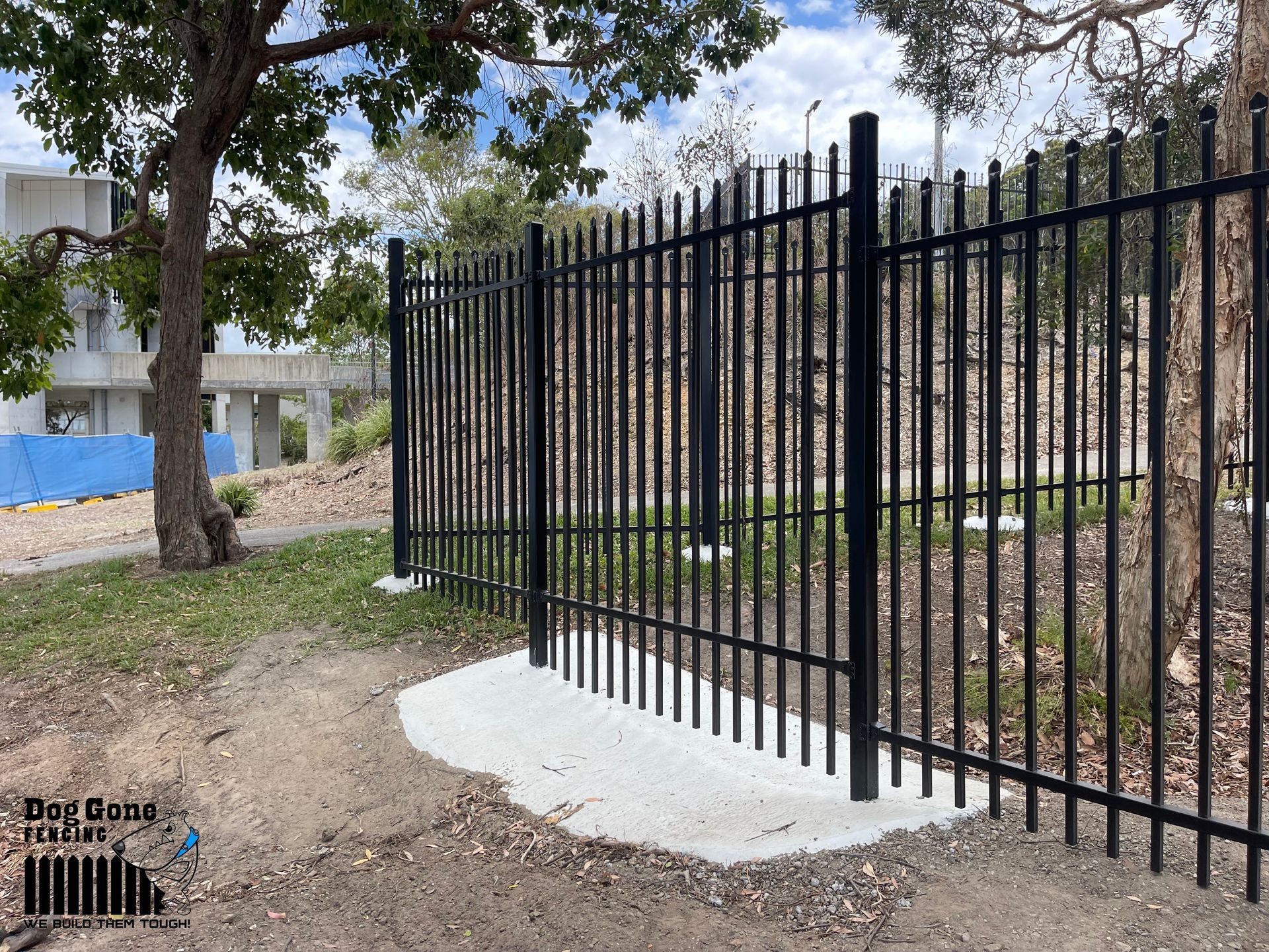A Black Metal Fence With A Tree In The Background — Dog Gone Fencing in Paget, QLD