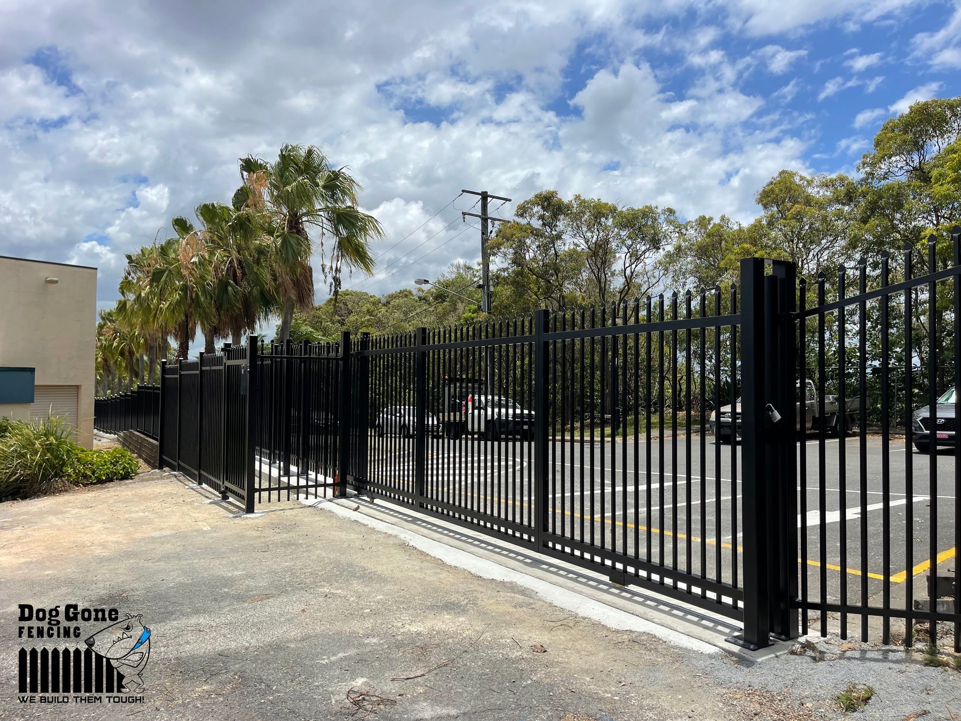 A Black Metal Fence Is Surrounding A Parking Lot — Dog Gone Fencing in Paget, QLD