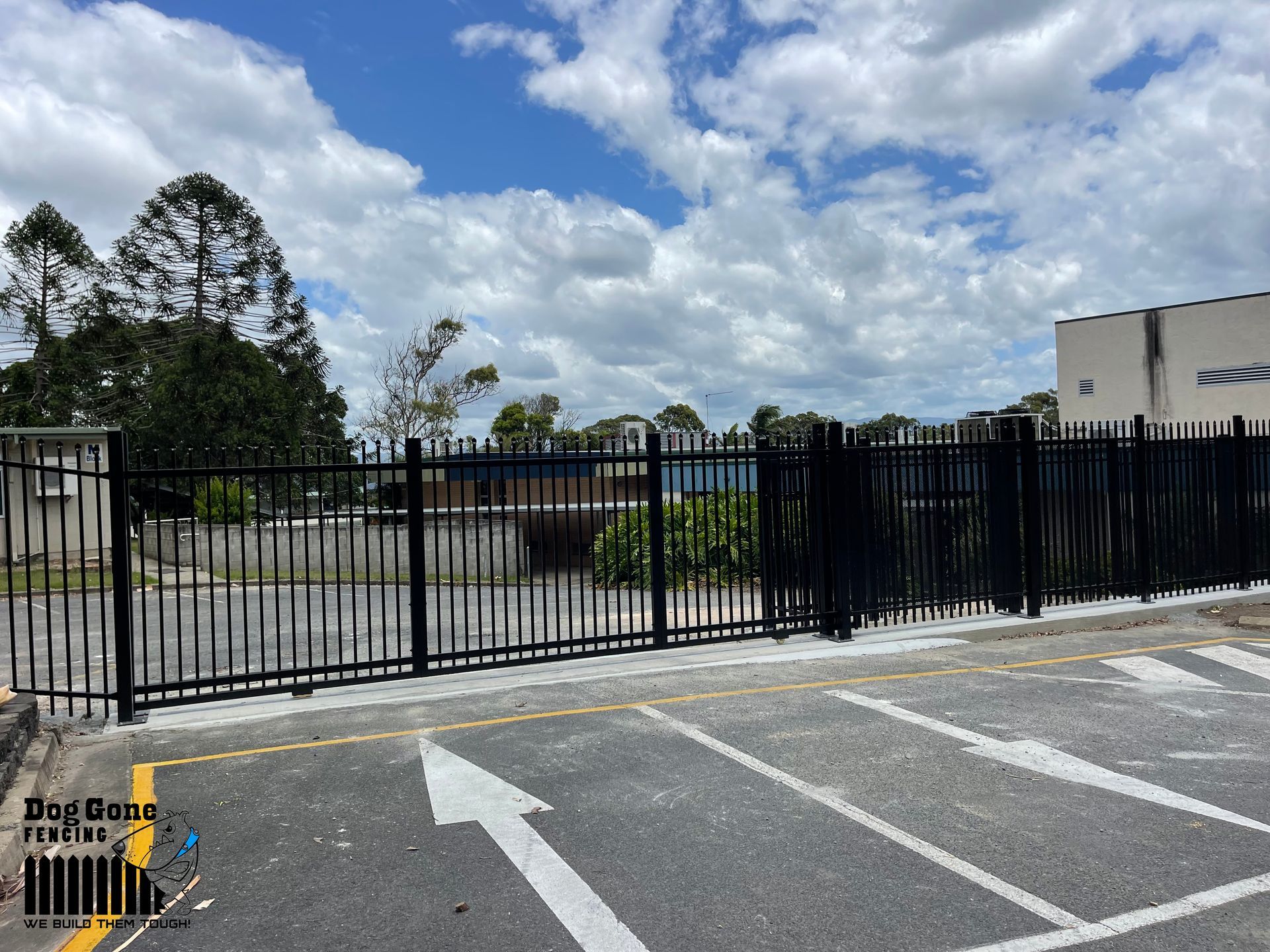 A Black Wrought Iron Fence Is Surrounding A Parking Lot — Dog Gone Fencing in Paget, QLD
