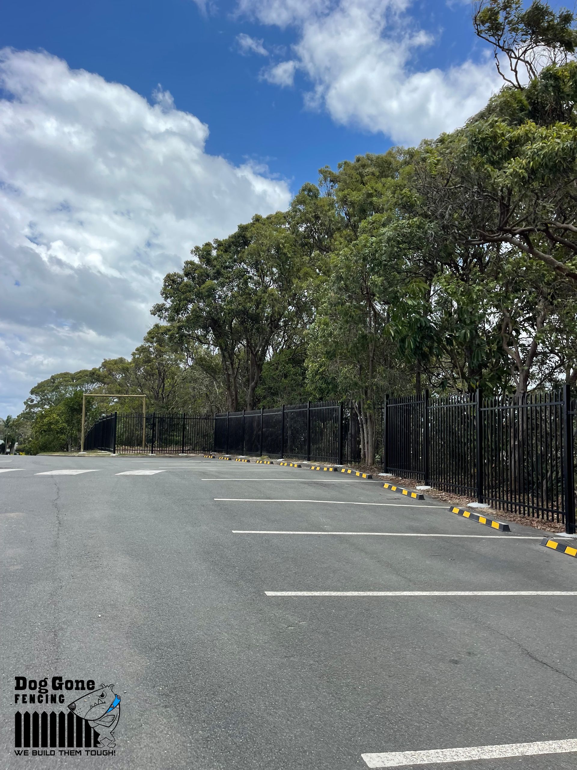 A Parking Lot With A Fence And Trees In The Background — Dog Gone Fencing in Paget, QLD