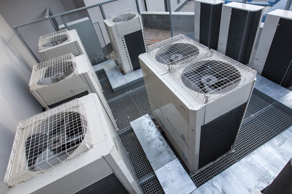 A bunch of air conditioners are sitting on top of a building.