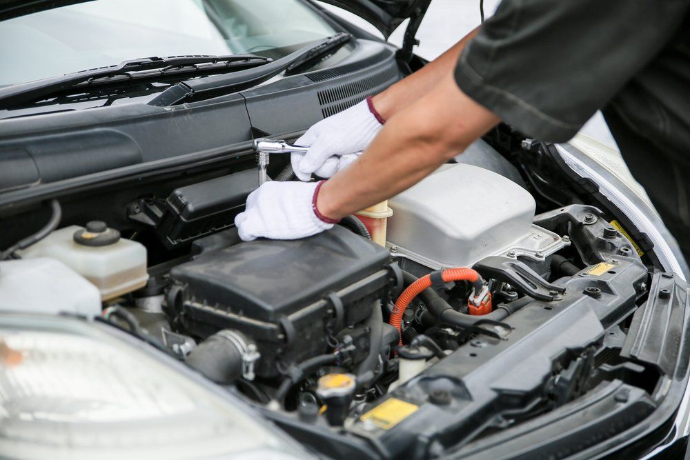Mechanic in white gloves working on a car engine with a wrench.