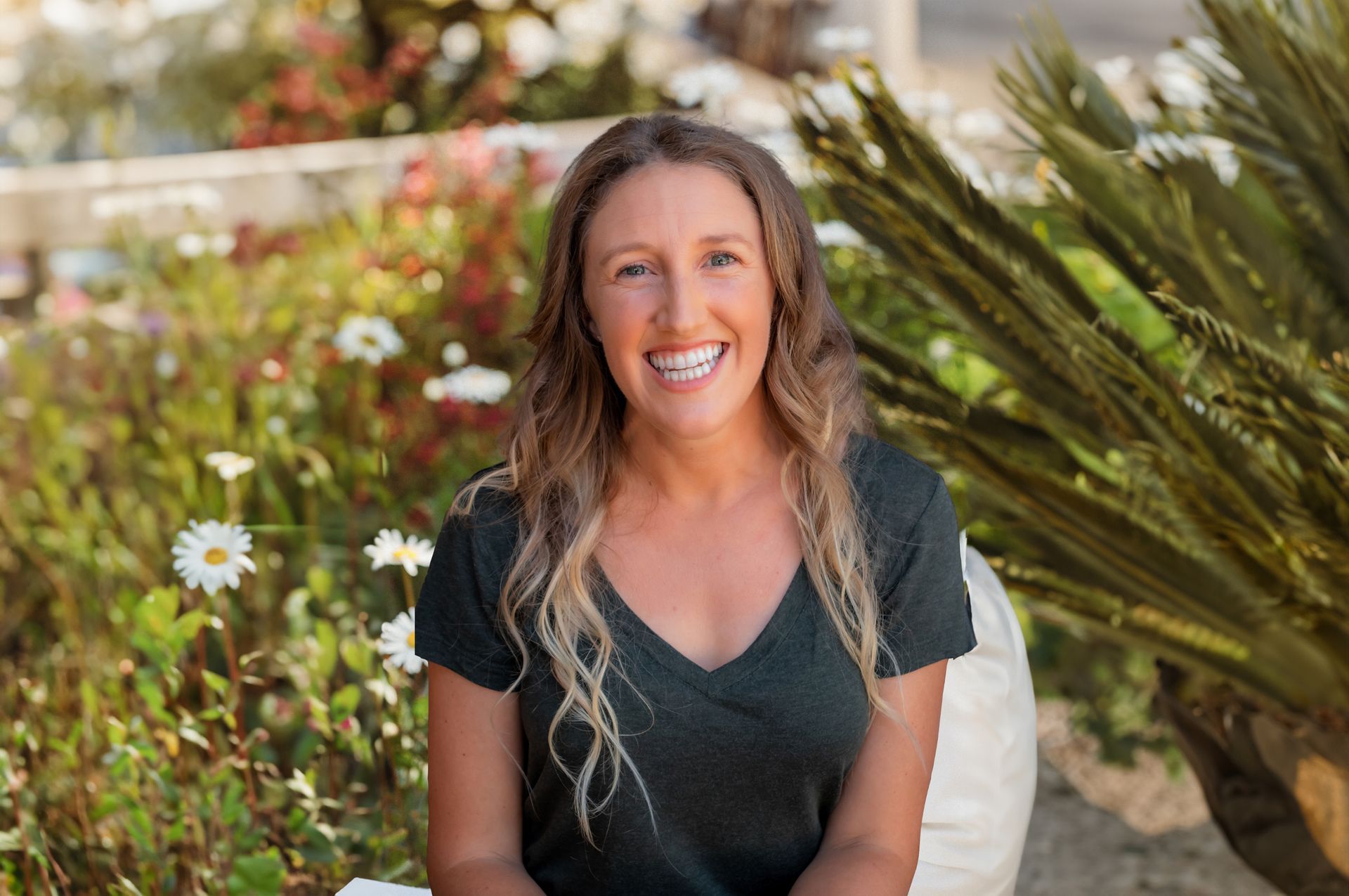 A woman is sitting in a chair in front of a field of flowers.