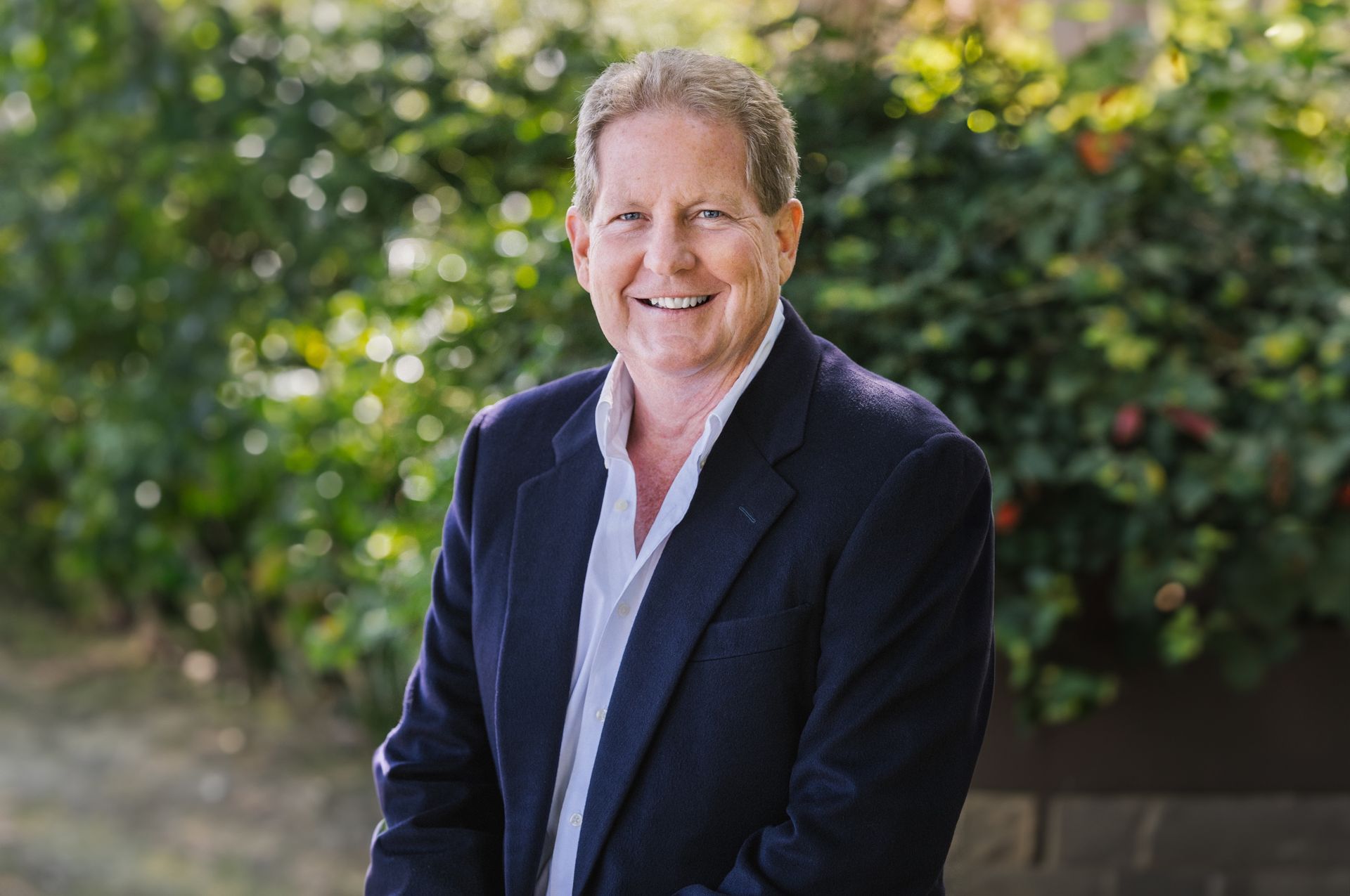 A man in a suit and white shirt is smiling for the camera.
