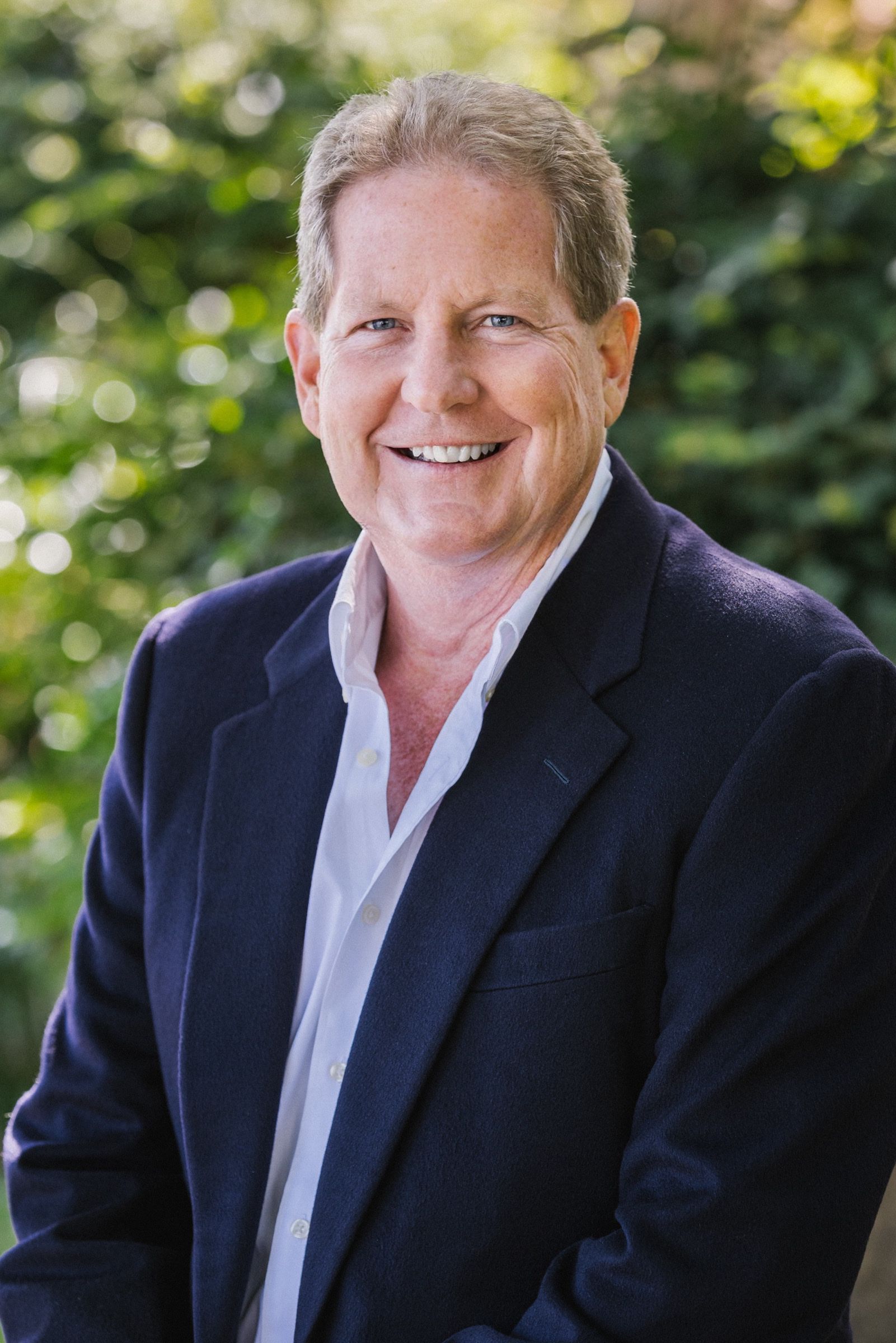 A man in a suit and white shirt is smiling for the camera.