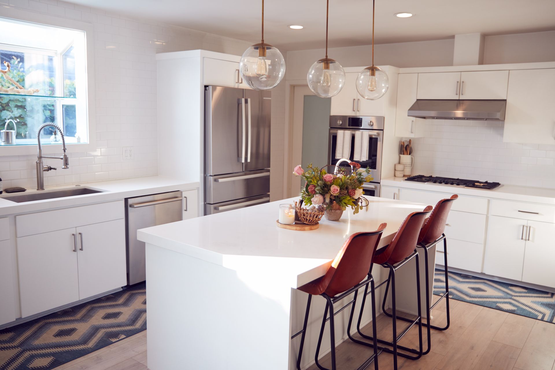 A kitchen with white cabinets , granite counter tops , stainless steel appliances and a large island.