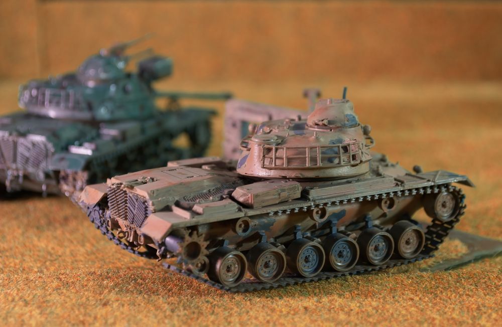 Two Model Tanks, One Brown and One Green, on a Brown Surface — Central Western Communications in Emerald, QLD