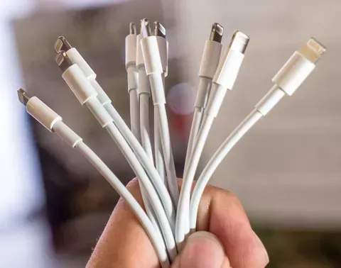 Hand Holding a Bundle of White Lightning Cables With Silver Connectors — Central Western Communications in Emerald, QLD