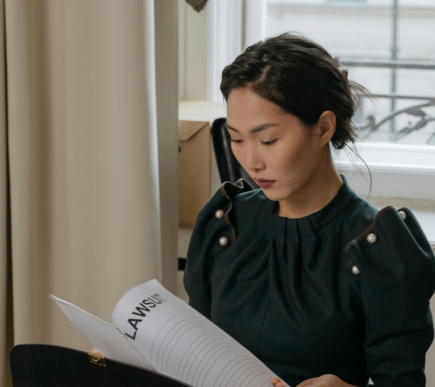 Coffee cup on saucer, laptop, and open books on a bed, suggesting work or study.