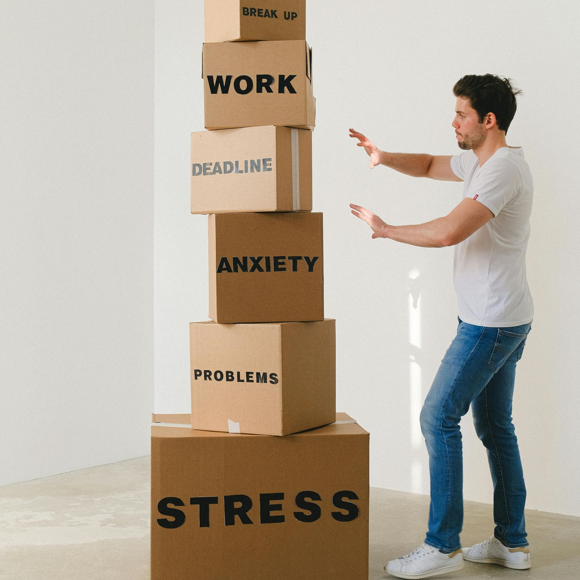 Man pushing away a precarious stack of boxes labeled 