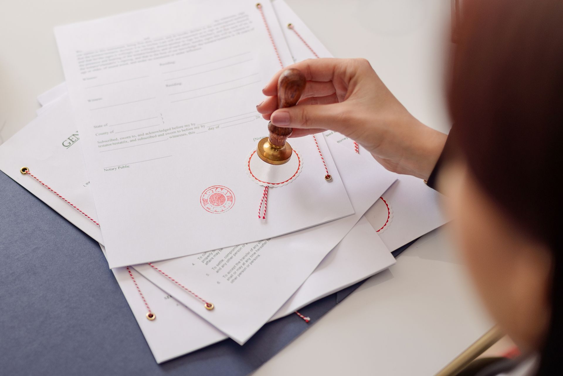 Hand stamping a red seal on stacked documents.