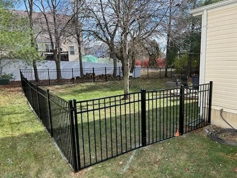 There is a black fence in the backyard of a house.