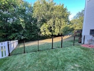 A backyard with a black fence and a white picket fence | Ellisville, MO | Americas fence & Deck Com
