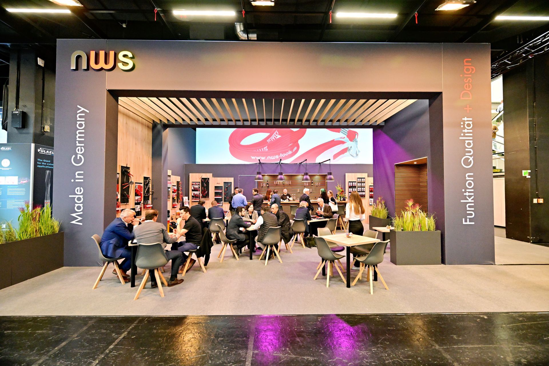 Eine Gruppe von Menschen sitzt in einem großen Raum an Tischen.