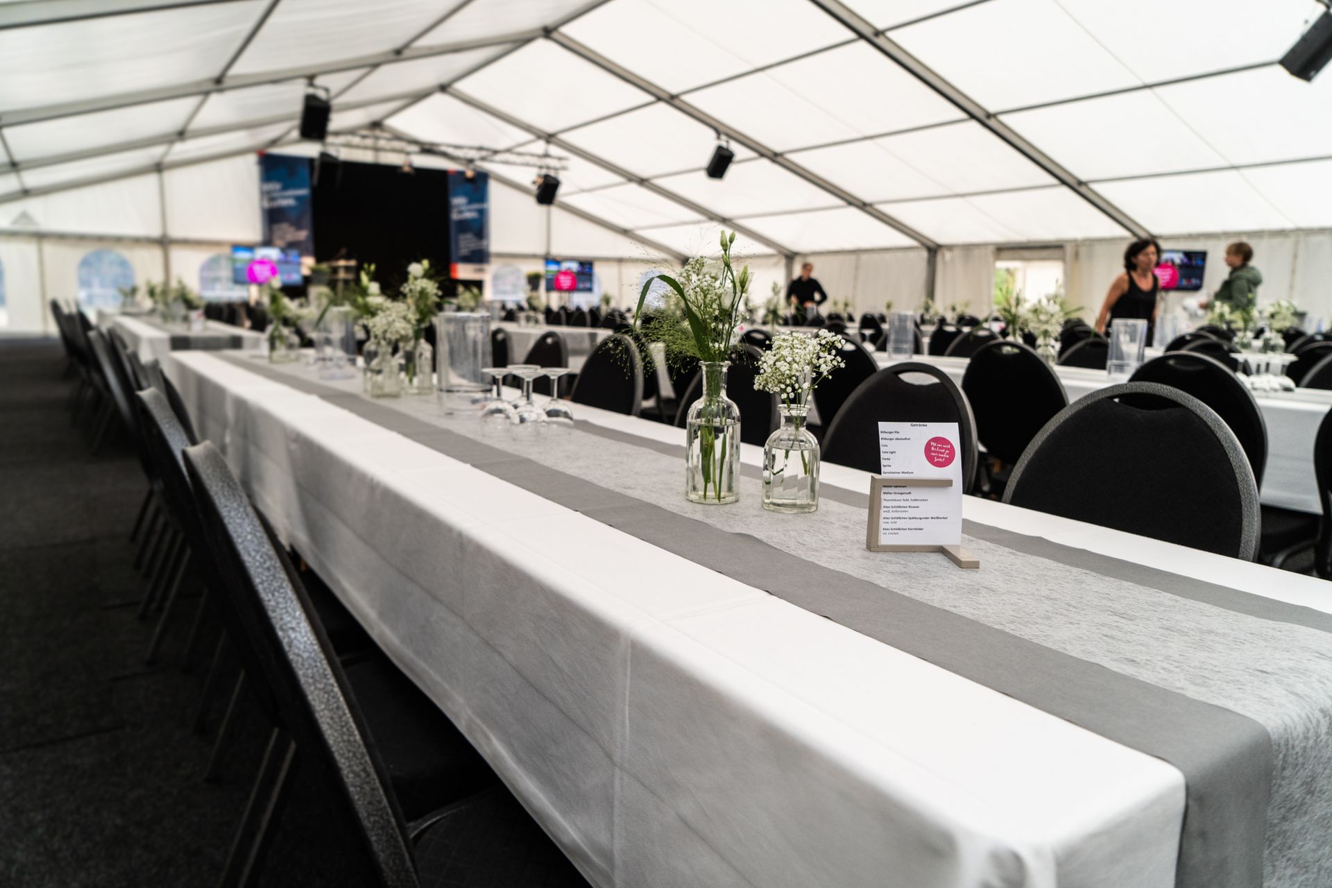 Ein langer Tisch in einem Zelt mit Blumen darauf