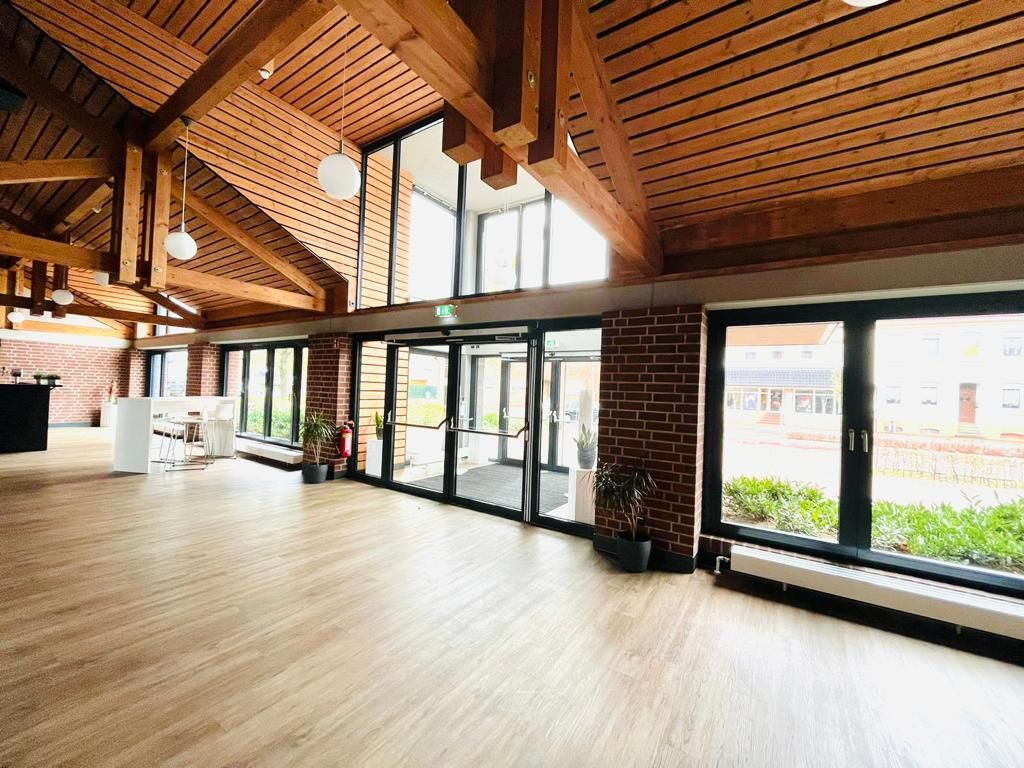 Ein großer leerer Raum mit vielen Fenstern und Holzbalken.