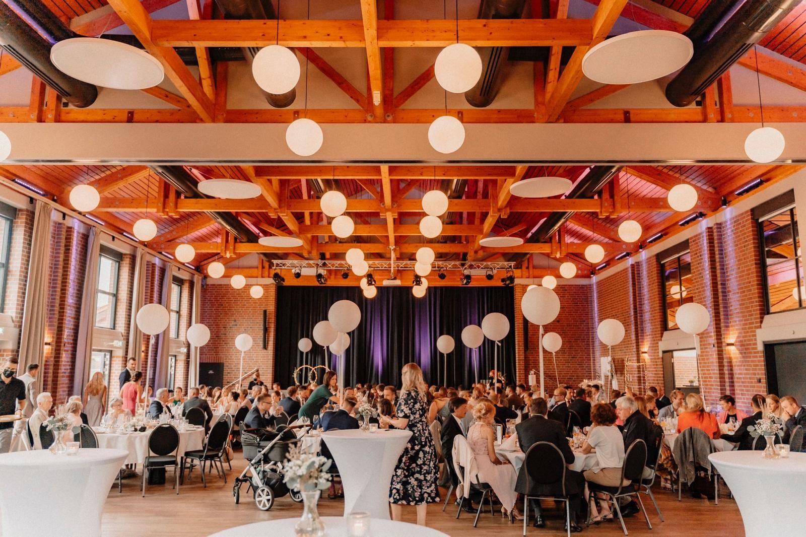 Ein großer Raum voller Menschen, die an Tischen und Stühlen sitzen.