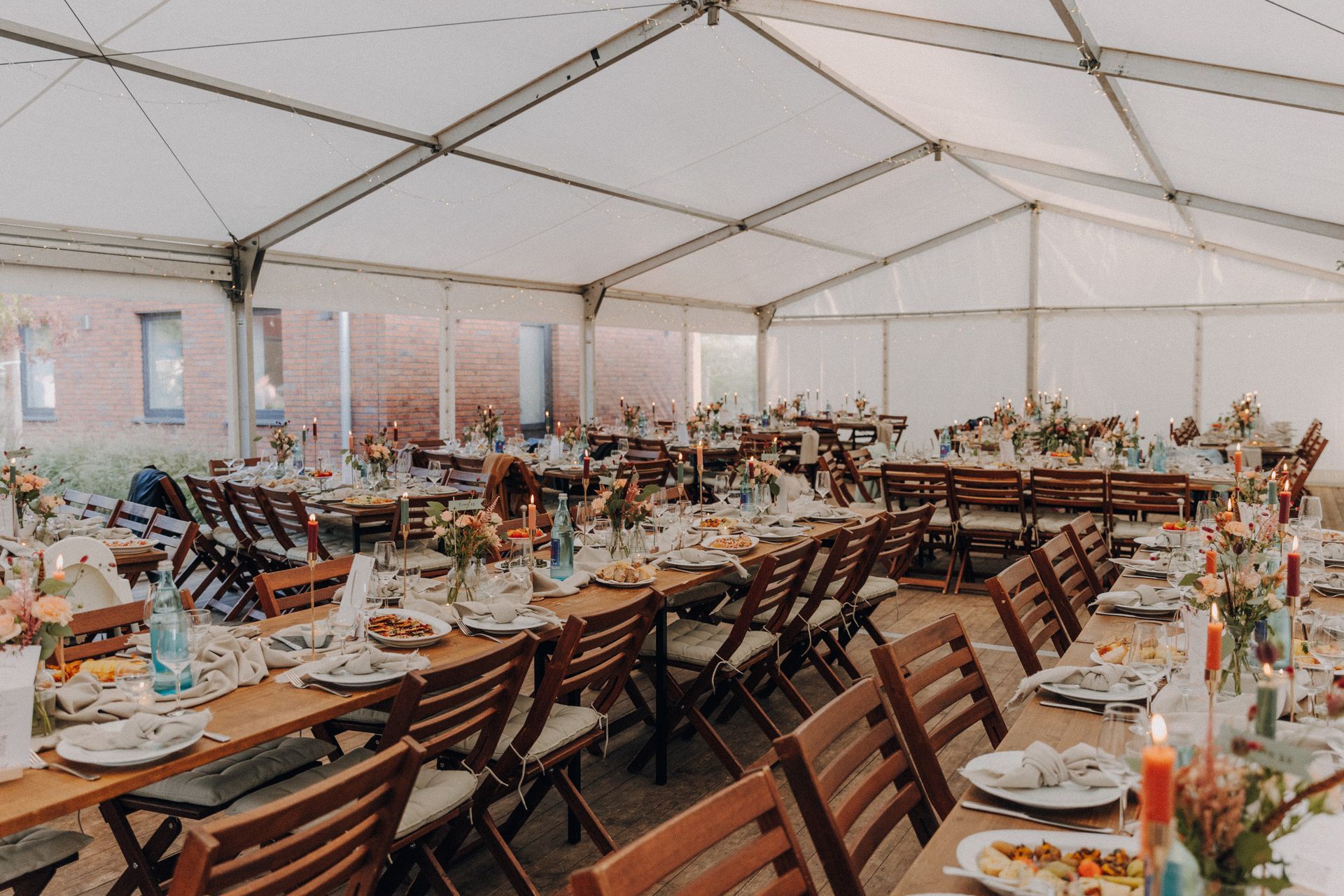 Ein großes Zelt mit Tischen und Stühlen für einen Hochzeitsempfang.