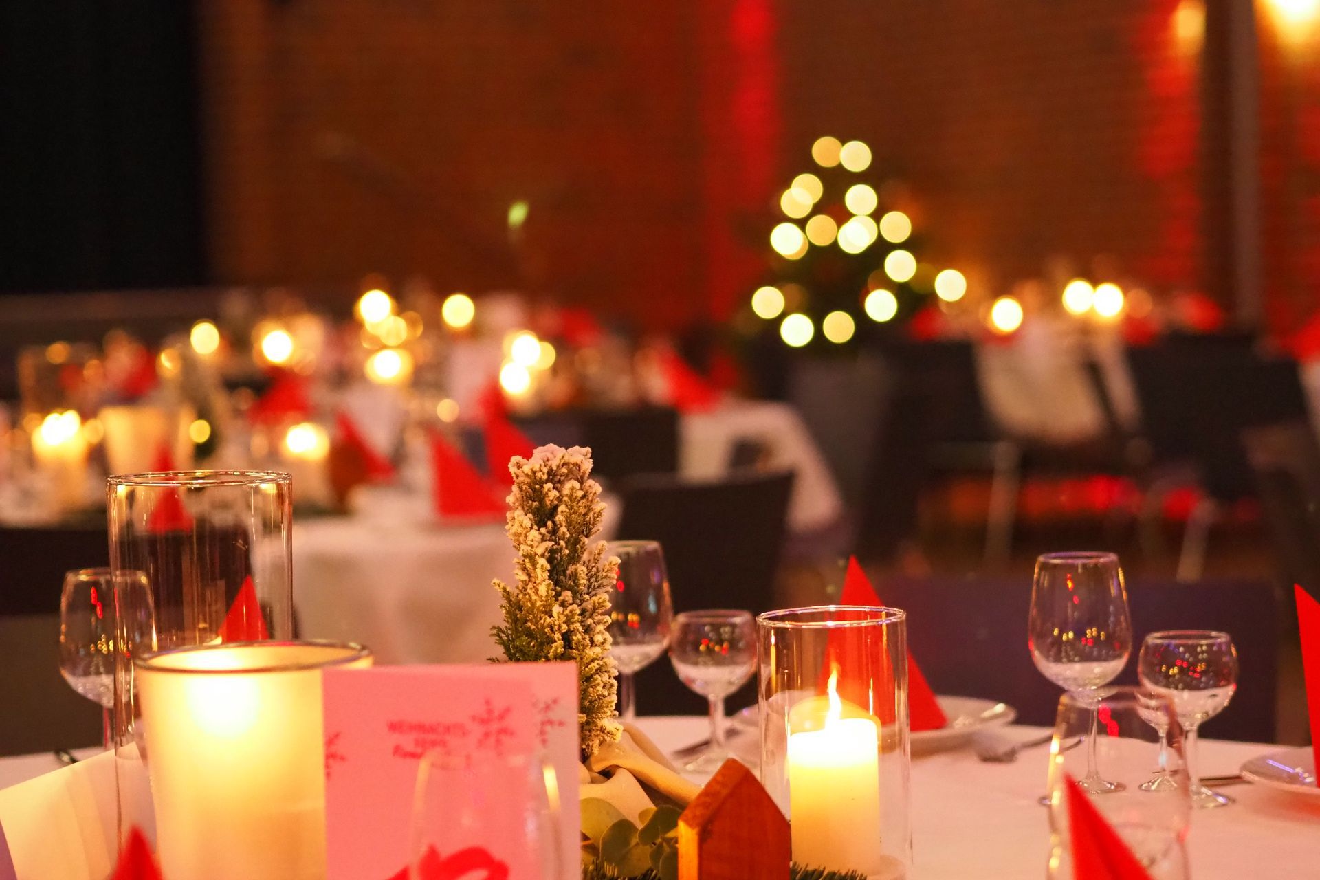 Eine weihnachtliche Tischdekoration mit Kerzen und einem Weihnachtsbaum im Hintergrund