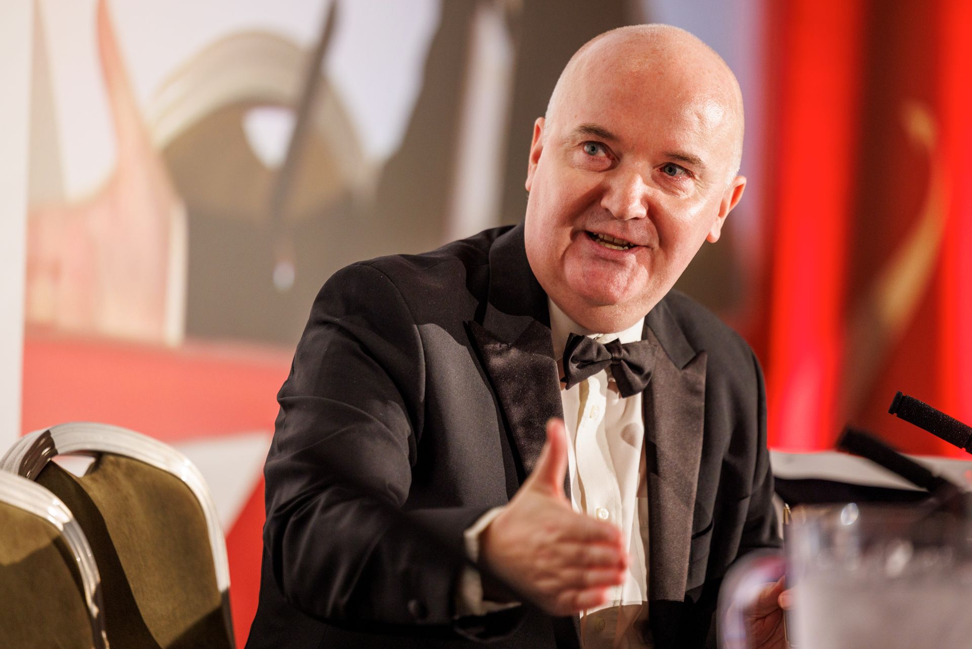 A man in a tuxedo is sitting at a table giving a thumbs up.