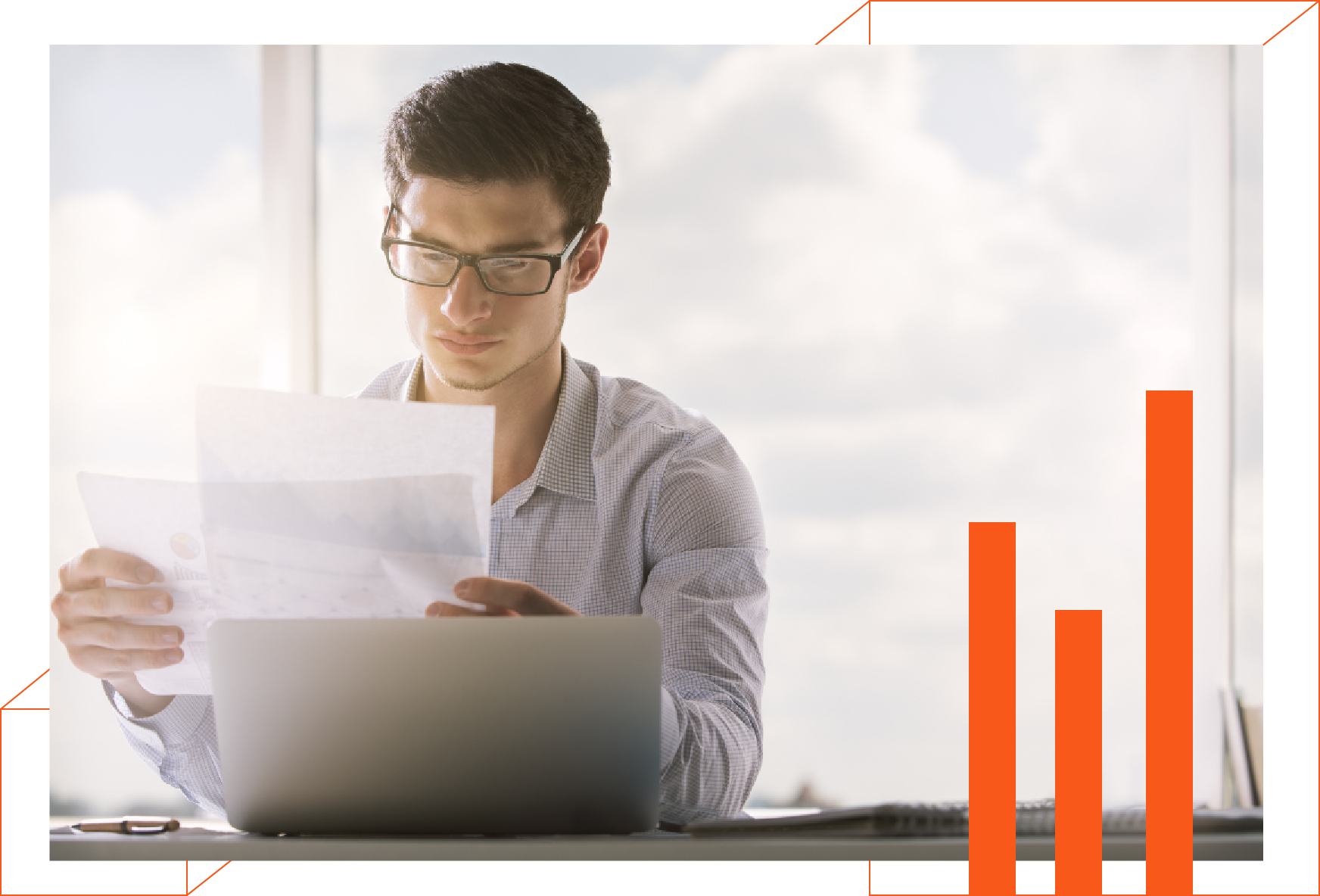 A man is sitting at a desk with a laptop and a piece of paper.