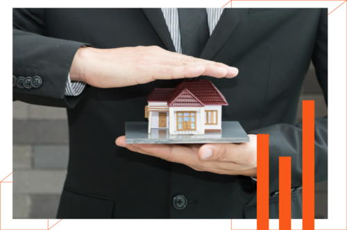 A man in a suit is holding a model house in his hands.