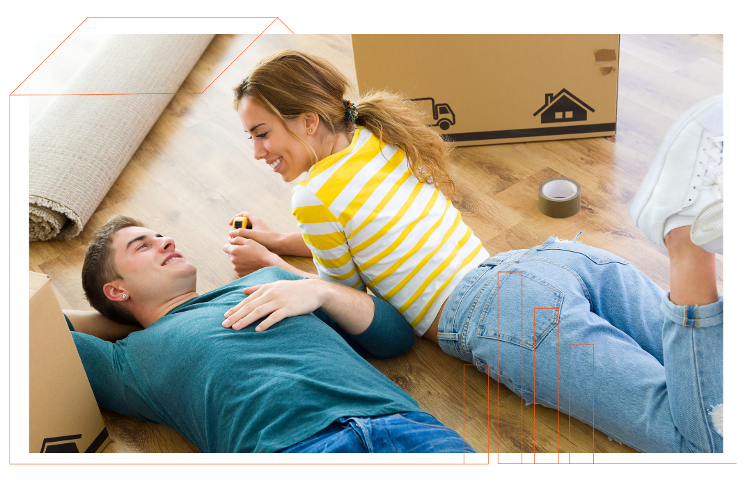 A man and a woman are laying on the floor next to moving boxes.